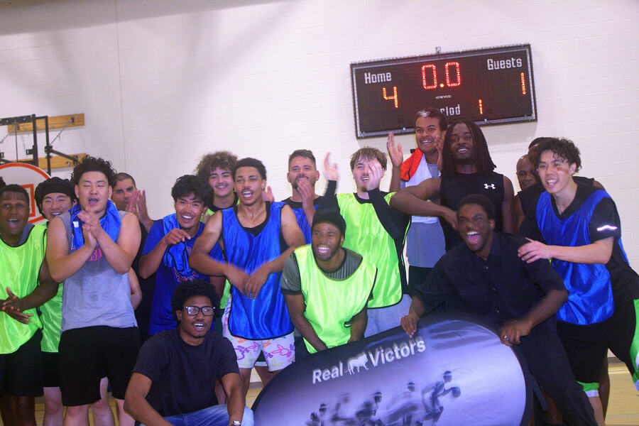 The whole run celebrating in front of the Real Victors banner and scoreboard